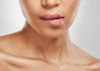 Obraz premium Biting, lips and closeup of gloss, beauty and cosmetics for aesthetic and skincare for healthy skin. Studio, white background and person with lipstick on mouth, makeup and dermatology benefits