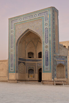 Ornate portal of Mir-i-Arab Madrasah in Bukhara featuring intricate tilework and pointed arch at dusk. Ideal for travel publications and cultural heritage projects.