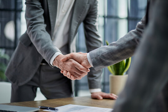 Two professionals shake hands over a signed document