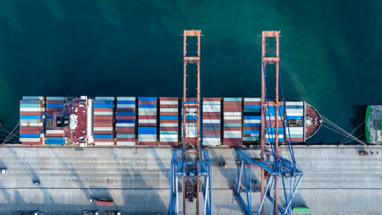 Fototapeta premium Aerial drone shot of crane loading containers onto cargo ship at Laem Chabang Port.