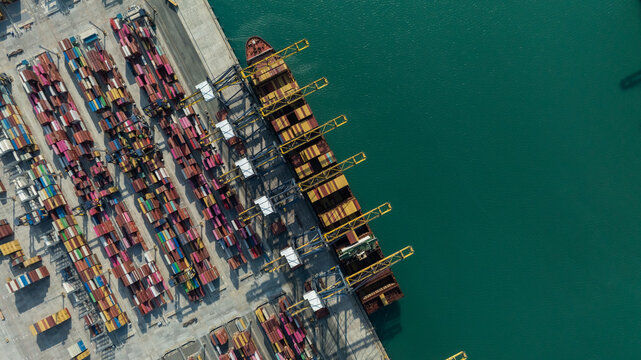 Aerial drone shot of crane loading containers onto cargo ship at Laem Chabang Port.