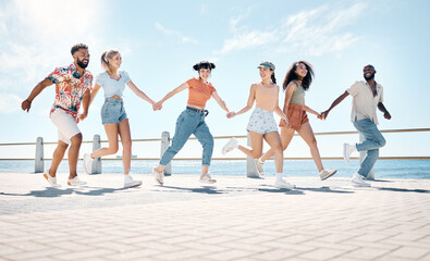 Obraz premium Happy, running and friends on promenade by sea for summer holiday, vacation and weekend. Travel, tourism and men with women by ocean for hangout, social gathering and holding hands on boardwalk
