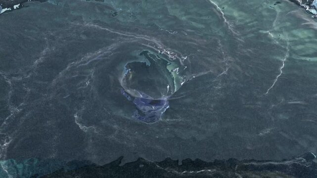 Aerial view of a water vortex turning fast with turbulences and the end of a hole in the center on a dark floor