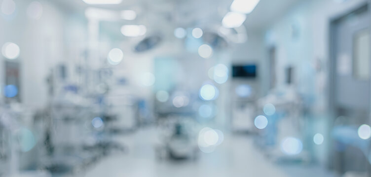A blurred view of a modern hospital operating room filled with medical equipment and bright lighting, conveying a clinical atmosphere of surgery.
