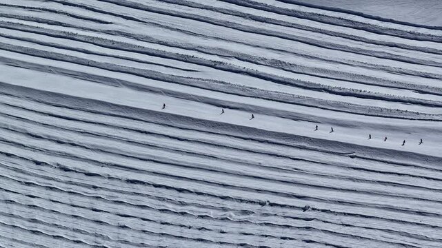 Sunny drone view of Tignes and Grande Motte glacier surrounded by snowy mountains in the French Alps during spring. Drone view of snowboarders and skiers riding on glacier in French Alps