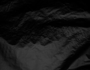 Abstract black fabric texture with deep folds and dramatic shadows in low light © shan