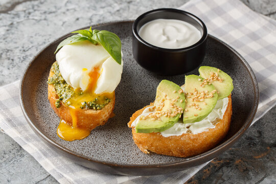 Keto sandwiches with poached eggs and basil pesto, as well as avocado and cream cheese, close-up on a plate on a table. Horizontal