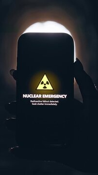 Vertical video. Smartphone Displaying Nuclear Emergency Warning in Dark Underground Tunnel, Cinematic Apocalypse Scene About Radiation Threat and Survival During Disaster