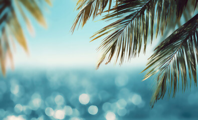 Fototapeta premium Tropical palm fronds frame a shimmering, sun-drenched ocean on a clear day