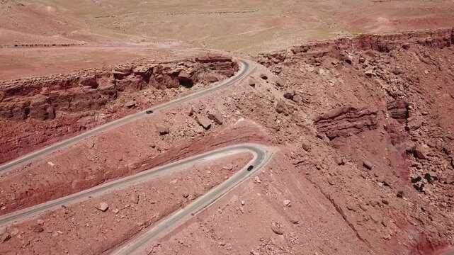 Aerial drone footage of a sharp hairpin turn road carved into rugged desert mountains in Morocco. Clean composition and strong leading lines create a visually striking scene ideal for travel, automoti