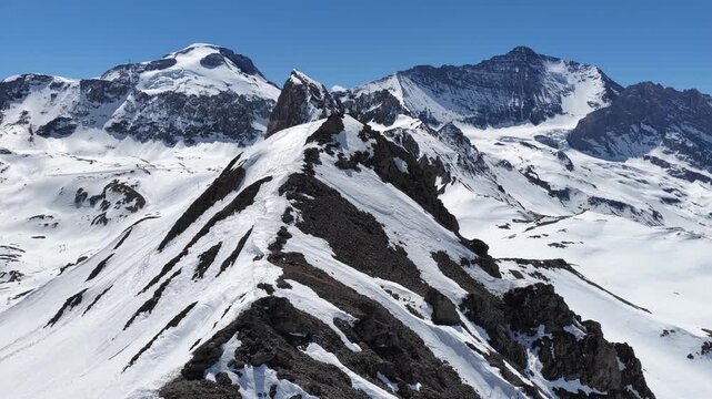 Sunny drone view of Tignes and Grande Motte glacier surrounded by snowy mountains in the French Alps during spring. Drone view of alpine glacier and snowy mountain peaks in French Alps