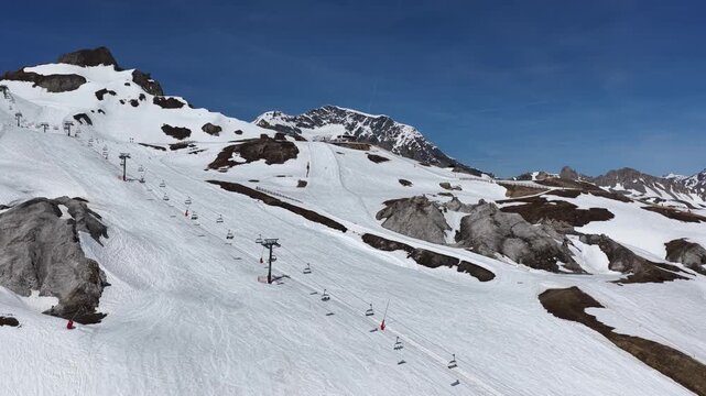 Drone view of snowboarders and skiers performing tricks on big air kickers in Tignes snowpark during sunny spring day in the French Alps. Freestyle snowboard and ski session on big air jumps in alps