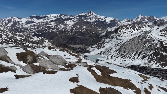 Drone view of snowboarders and skiers performing tricks on big air kickers in Tignes snowpark during sunny spring day in the French Alps. Freestyle snowboard and ski session on big air jumps in alps