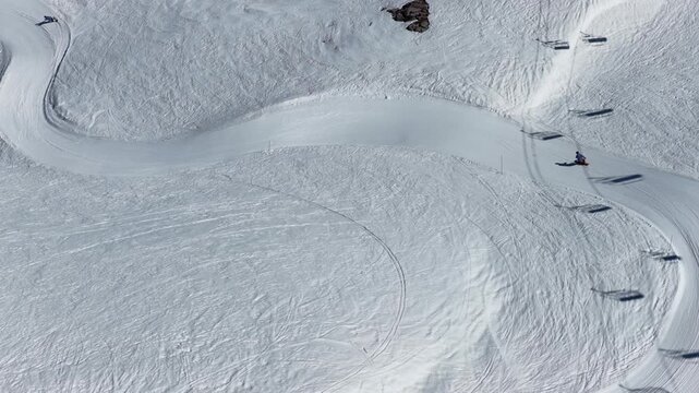 Spring sunshine over Val d'Isere ski resort in the French Alps, snowboarders riding a snowboard cross course on soft snow, alpine scenery with mountains, blue sky in sunny spring. Tignes, France