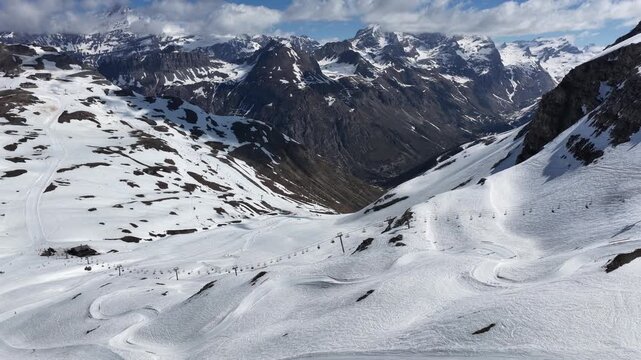 Spring sunshine over Val d'Isere ski resort in the French Alps, snowboarders riding a snowboard cross course on soft snow, alpine scenery with mountains, blue sky in sunny spring. Tignes, France