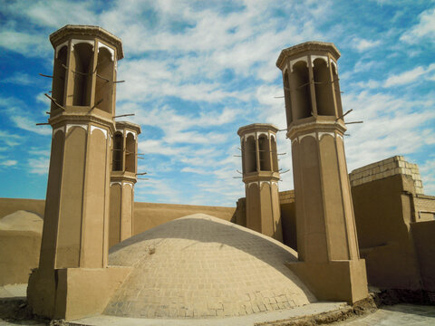 Traditional windcatcher towers rise above adobe desert architecture under a vibrant blue sky. Perfect for cultural heritage, sustainable design, and travel marketing themes.