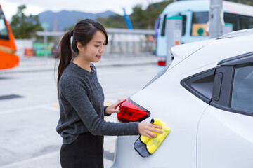 Female owner wiping car light at parking lot © leungchopan