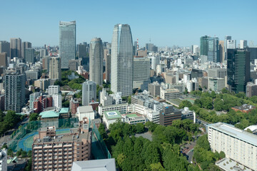 Obraz premium Panoramic view of Tokyo's dense urban landscape with modern skyscrapers and lush greenery