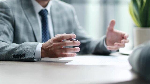 Man in suit holds pen, poised to sign document
