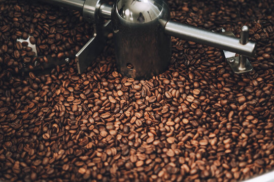 Close-up view of freshly roasted coffee beans inside a commercial roaster machine, showing the rich brown color and texture of the beans.