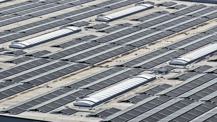 This high-resolution aerial photograph showcases an extensive rooftop solar photovoltaic system installed on a large industrial or commercial building.  © Maik