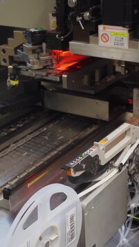Vertical video. SMD feeder components. Supply system for surface mount device components via tape reels. Image showing tape reel feeder used for surface mount device components in manufacturing