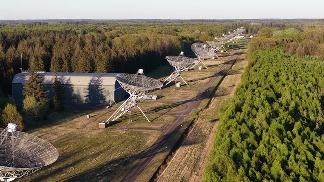 Impressive aerial perspective of the westerbork synthesis radio telescope, a series of parabolic antennas aligned in a row for astronomical research, surrounded by a lush green forest