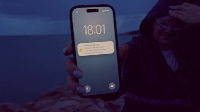 Close Up Smartphone Hurricane Warning Notification During Strong Coastal Storm at Dusk, Extreme Weather Awareness and Personal Safety