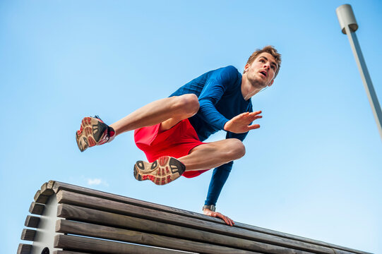 Young sporty man jumping over a bench