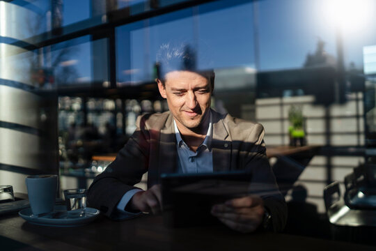 Businessman using tablet behind the window in a cafe