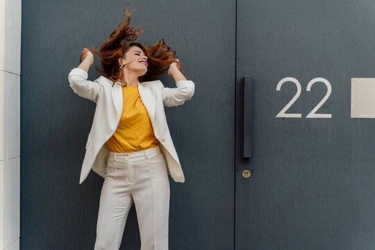 Businesswoman in white pant suit, standing in front of entrance door