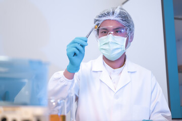 Fototapeta premium Scientist using tweezers holding yellow softgel capsule in laboratory, inspecting vitamin oil capsule for quality control. Health supplement innovation development in science facility