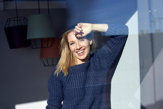 Portrait of laughing blond woman behind windowpane