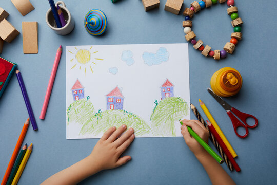Child drawing landscape with houses