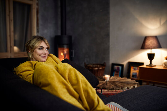 Portrait of smiling woman relaxing on couch at home in the evening