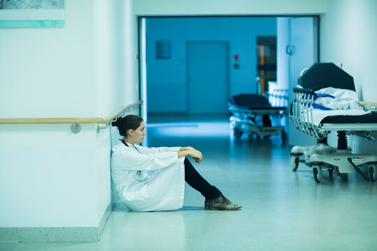 Overstressed young doctor sitting on hospital corridor