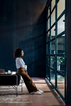 Young businesswoman looking out of window in loft office