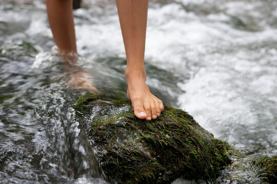 Austria, Salzkammergut, Mondsee, feet of teenage girl crossing a brook