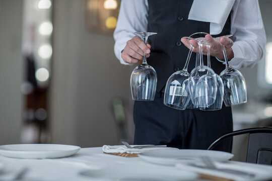 Waiter placing wine glasses on restaurant table