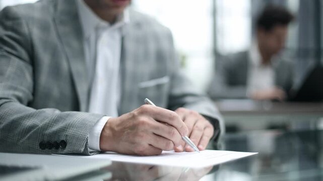 Man signs document with focused, serious expression