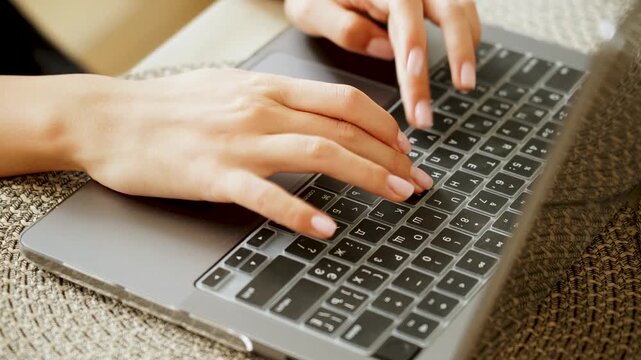 Hands typing on a gray laptop keyboard with a clear silicone cover indoors