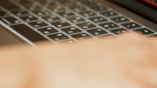 Typing on a dual language laptop keyboard with a silicone cover indoors