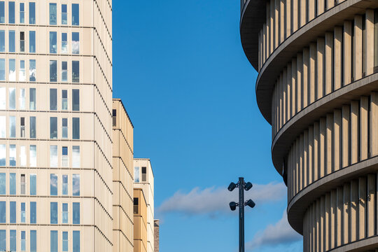 Curved modern architecture cuts into a blue sky in Stockholm, Sweden, framing an urban city building facade with crisp Nordic geometry