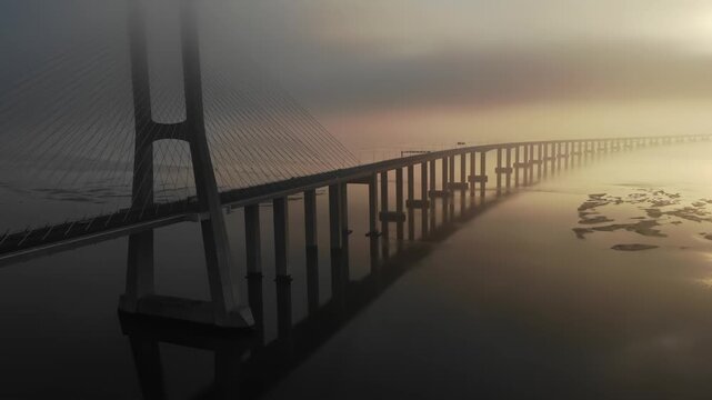 Aerial view of vasco da gama bridge over tagus river during misty sunrise in lisbon portugal.