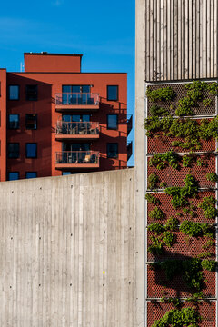 concrete facade cuts across Nordic residential urban architecture, where plants climb near brick walls and balconies behind the exterior plane