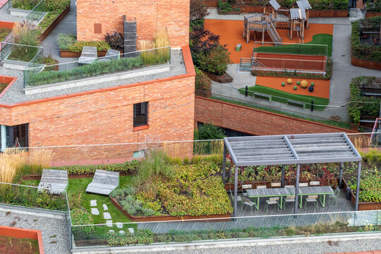 Elevated Nordic residential architecture view over a brick courtyard garden, where terrace benches and plants shape a compact urban outdoor space