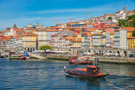 Ribeira waterfront in Porto, Portugal, with rabelo boats and tourist boats on the Douro River below old town buildings