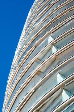 Curved glass balconies rise through blue sky in Benidorm, Spain, turning a modern building facade into fluid urban architecture geometry