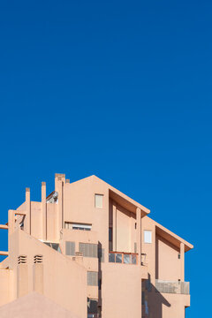 A pale residential building in Benidorm, Spain sets modern urban architecture against deep blue sky, balancing facade geometry with coastal light