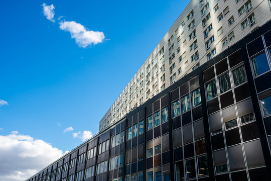 Modern building facade and windows stretch in perspective across urban architecture and cityscape in Paris, France, against a clear sky